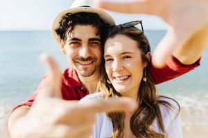 Happy Couple Enjoying Summer Vacation On The Beach - Man Making