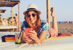 Woman on beach with cellphone in vacation