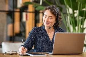 Successful young business woman working on laptop with headphone