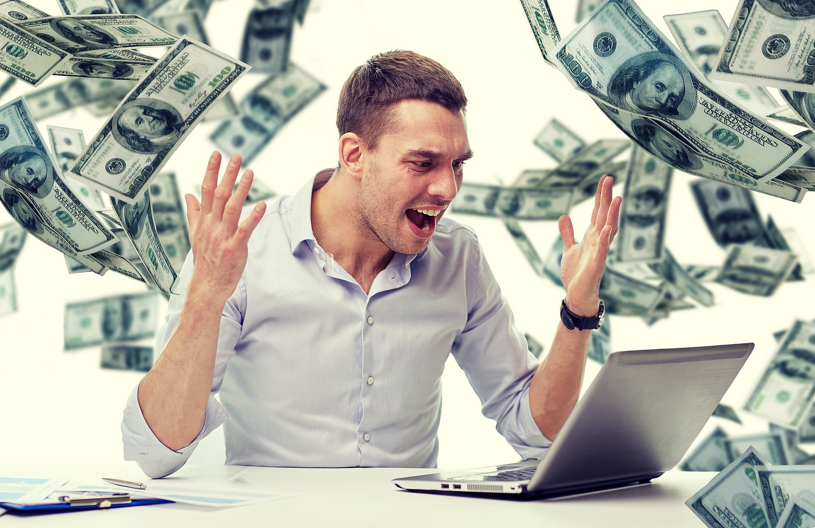 angry man in front of laptop with dollar bills on the background