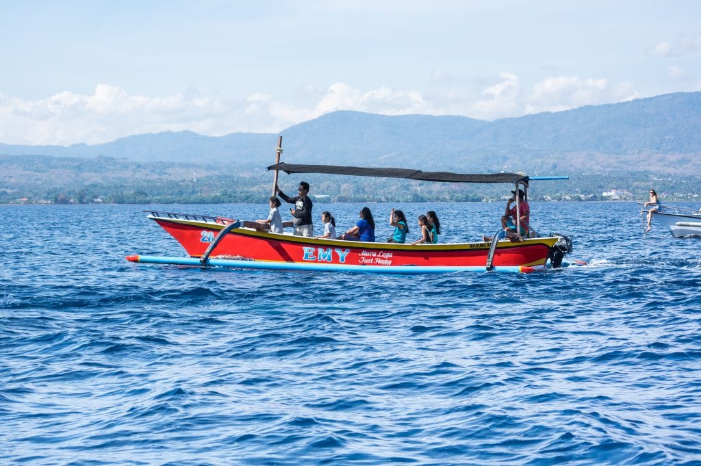 Tourists looking for dolphins from boats at Lovina beach of Bali, Indonesia. Popular activities for visitors include early-morning boat trips to see dolphins