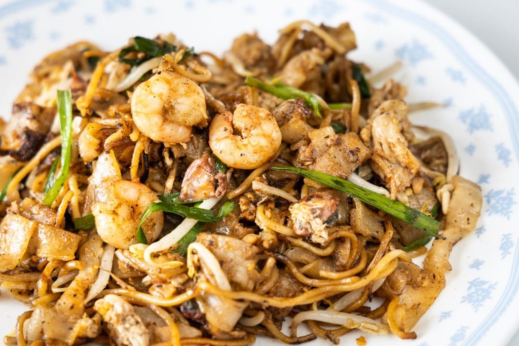 Close-up on Penang char kuey teow is popular fried noodle with coceral, shrimp and eggs in black sauce in Malaysia