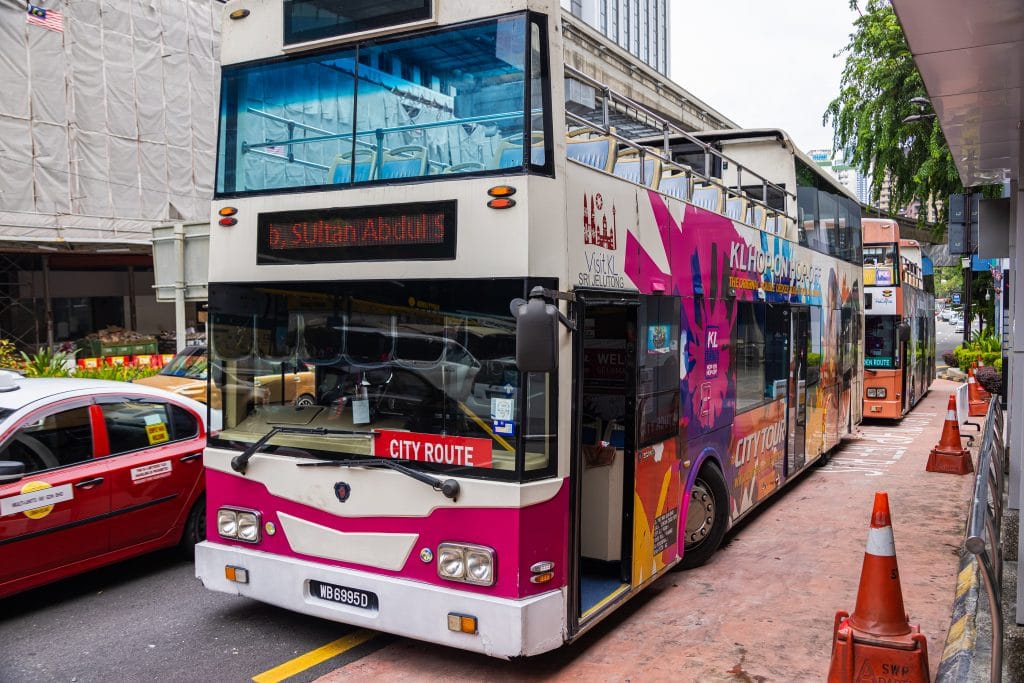 Kuala Lumpur, Malaysia - October 04, 2020: Empty double deck sightseeing buses on the streets of Kuala Lumpur. Absent tourists leave tourist buses empty due to corona lockdown and travel restrictions