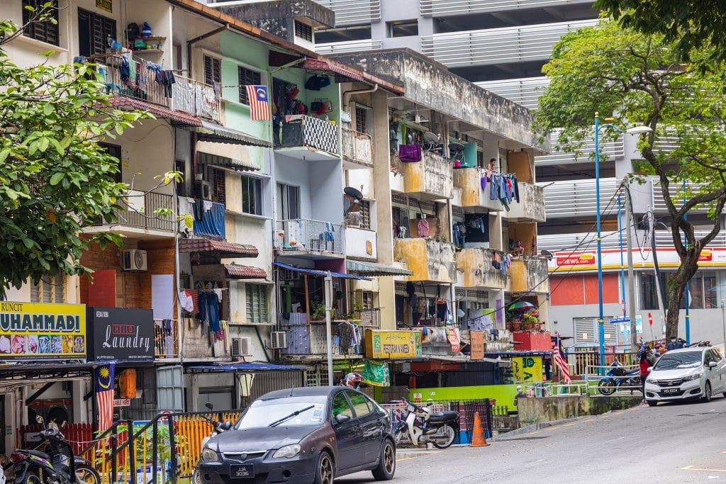 Kuala Lumpur, Malaysia - October 04, 2020: The dirty back roads of Kuala Lumpur. Behind the scenes of the metropolis. The chaotic cityscape and the run down houses with the Malaysian flag