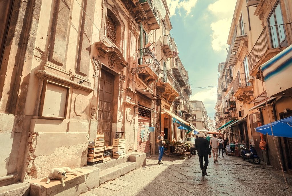PALERMO, ITALY: Old city streets ith stray dog and people walking around markets and stores of historical center on 10 October, 2019. Sicily is Italian region with highest number of expatriates