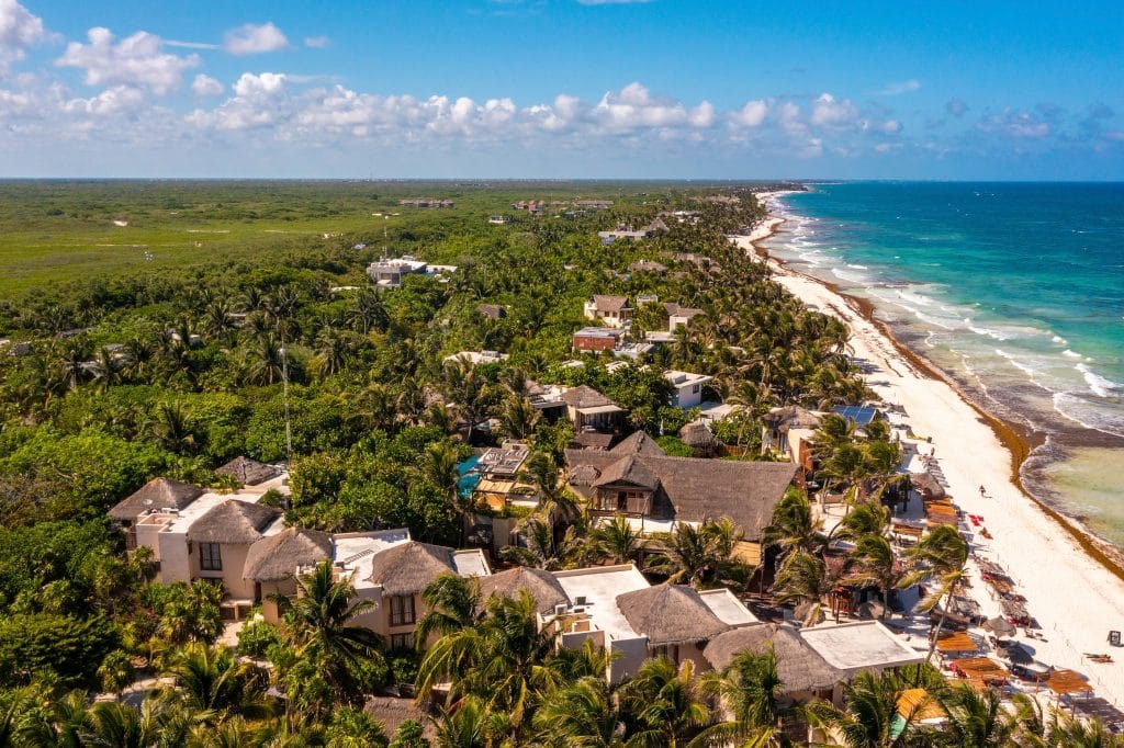 Aerial Tulum coastline by the beach with a magical Caribbean sea and small huts by the coast.