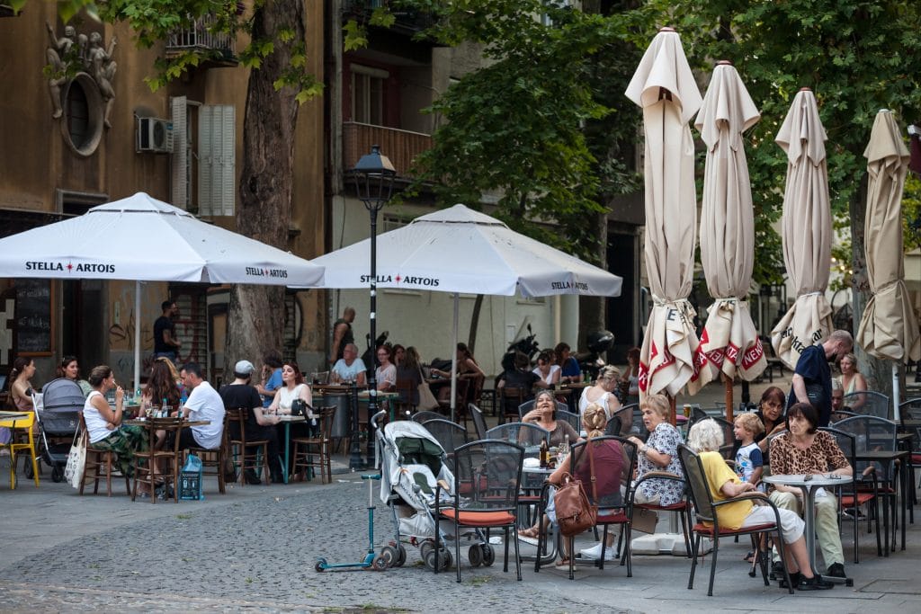 BELGRADE, SERBIA - JUNE 12, 2021: Selective blur on senior women, grandmothers with their grandchildren, sitting at the patio terrace of a cafe, crowded, in the city center of Belgrade.