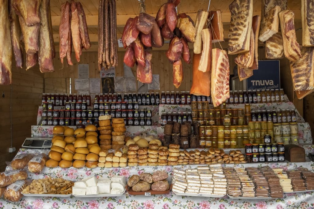 Brasov, Romania - July 10, 2021: Local Romanian food products displayed on market stall at the Transfagarasan road pass, Romania. Meat products, smoked cheese, honey, jam and bread for sale