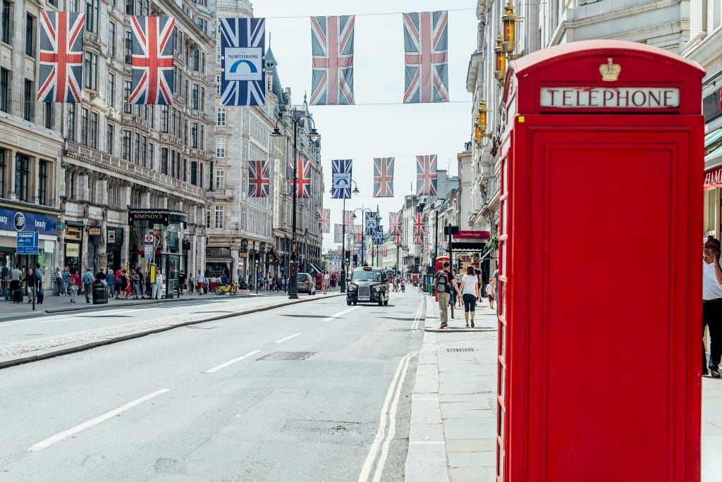 LONDON, UK - 24 June, 2018: Pre pandemic London with big crowd, lots of people, such as tourists and shoppers at Covent Garden area. Red telephone booth as a symbol of London and England, UK.