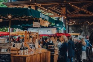London, UK - October 17, 2021: People and stalls inside Borough Market, one of the largest and oldest food markets in London, on a Sunday afternoon.