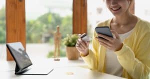 Close up of girl hold bank credit card, shopping online using mobile phone