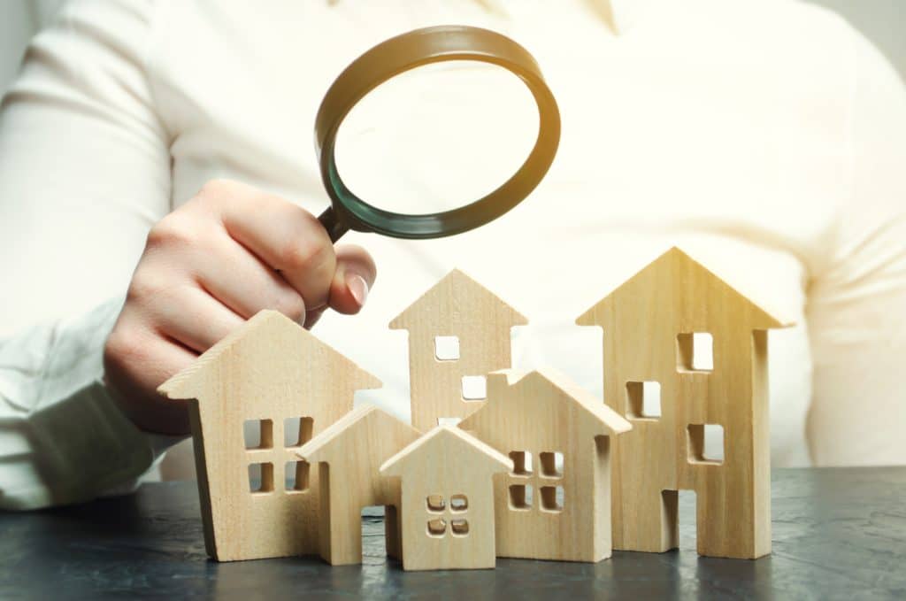 A woman is holding a magnifying glass over a wooden houses