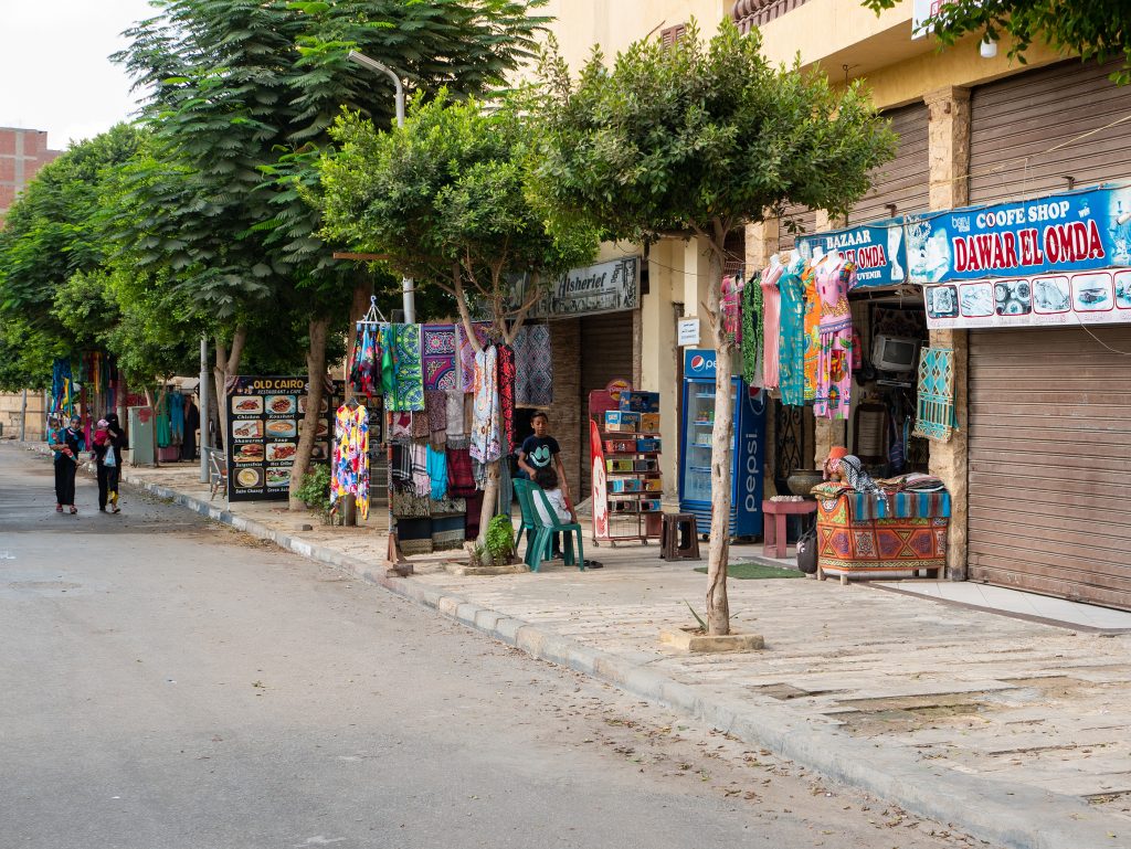Cairo, Egypt - September 30, 2021: Cairo street with local tourist shops and cafes. Women in traditional clothes are walking down the street with children in their arms.