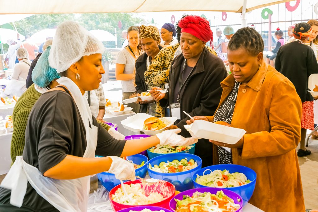 Johannesburg, South Africa - March 24, 2018: Soup Kitchen community outreach catering staff dishing up meals for African children