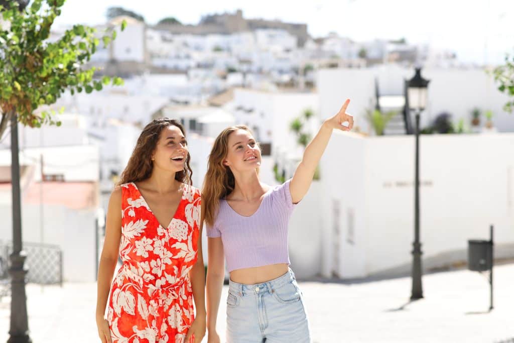 Two friends pointing standing in a town street on summer