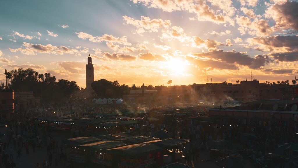 Yamaa el Fna Square with its markets and crowds of people and the tower of the mosque in the background, at sunset. Travel concept. Marrakech, Morocco