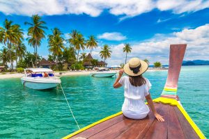 Happy traveler woman relaxing on boat near tropical island in Thailand