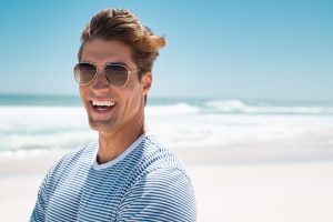 Portrait of handsome young man wearing sunglasses and looking at