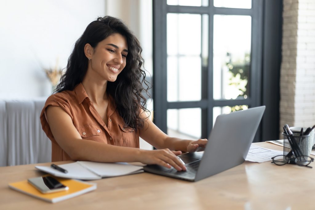 Young smiling Caucasian woman working on laptop from home