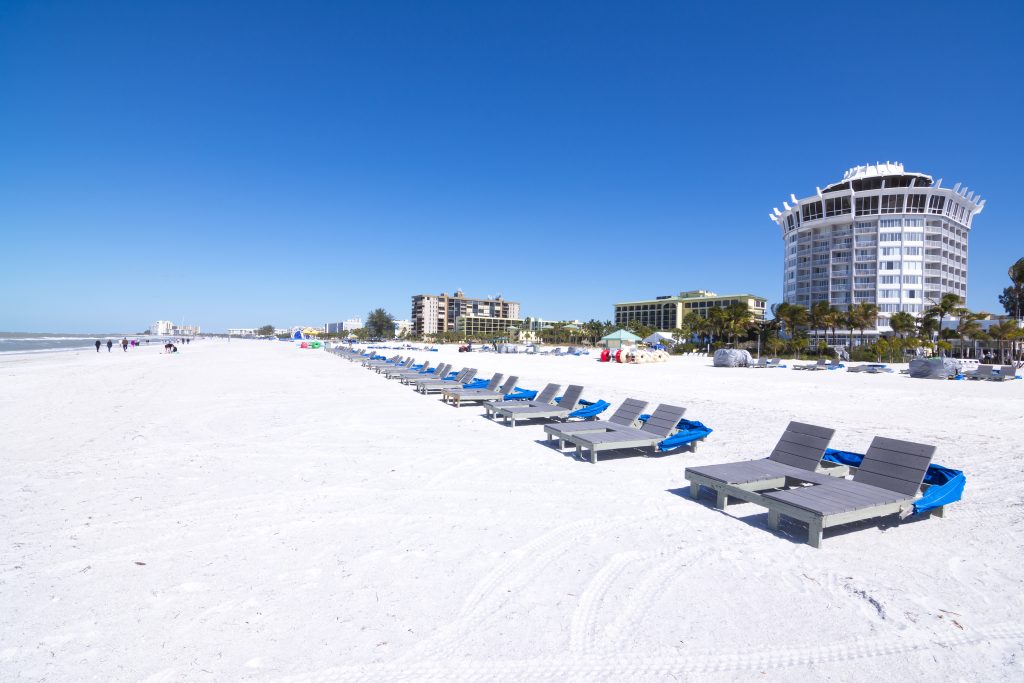 Resort and hotel lounge chairs lined up on clean white sand under clear blue sky at beautiful St. Pete Beach in St. Petersburg Florida ** Note: Soft Focus at 100%, best at smaller sizes
