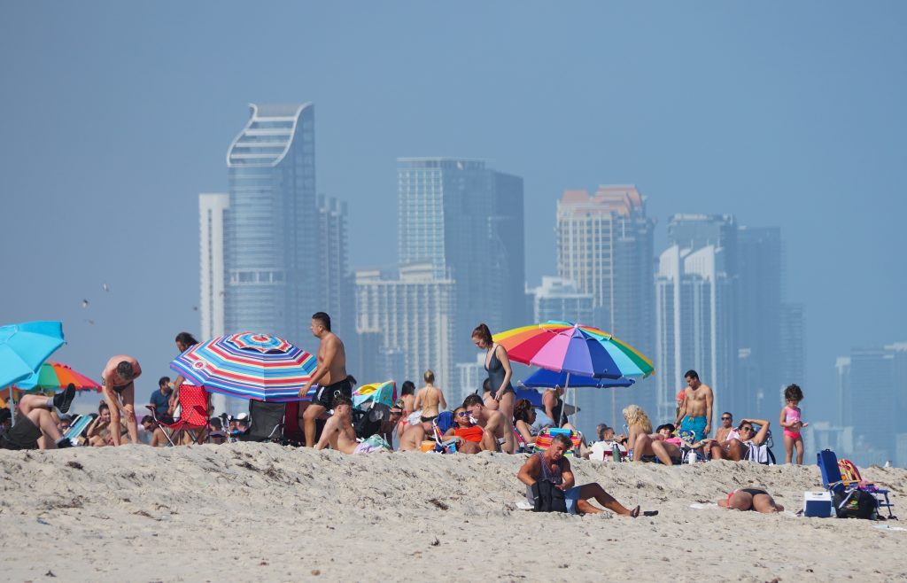 Miami Beach, Florida, U.S.A - February 18, 2022 - Visitors relaxing on the beach overlooking the downtown Miami
