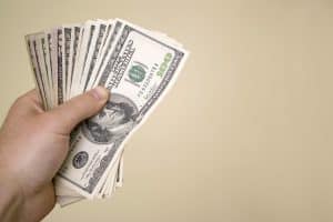 A handful of cash isolated over a gold background