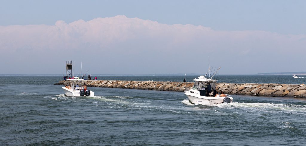 Hampton Bays, New York, USA - 6 June 2020: Two moter boat next to a rock jetty entering the Great Peconic Bay after going through the Shinnecock canal.