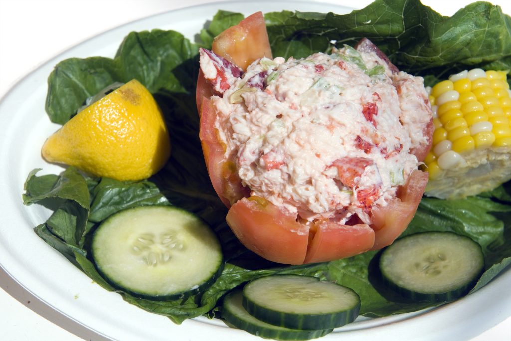 lobster salad stuffed in tomato with cucumber tomato lettuce on a platter in The Hamptons Montauk New York USA